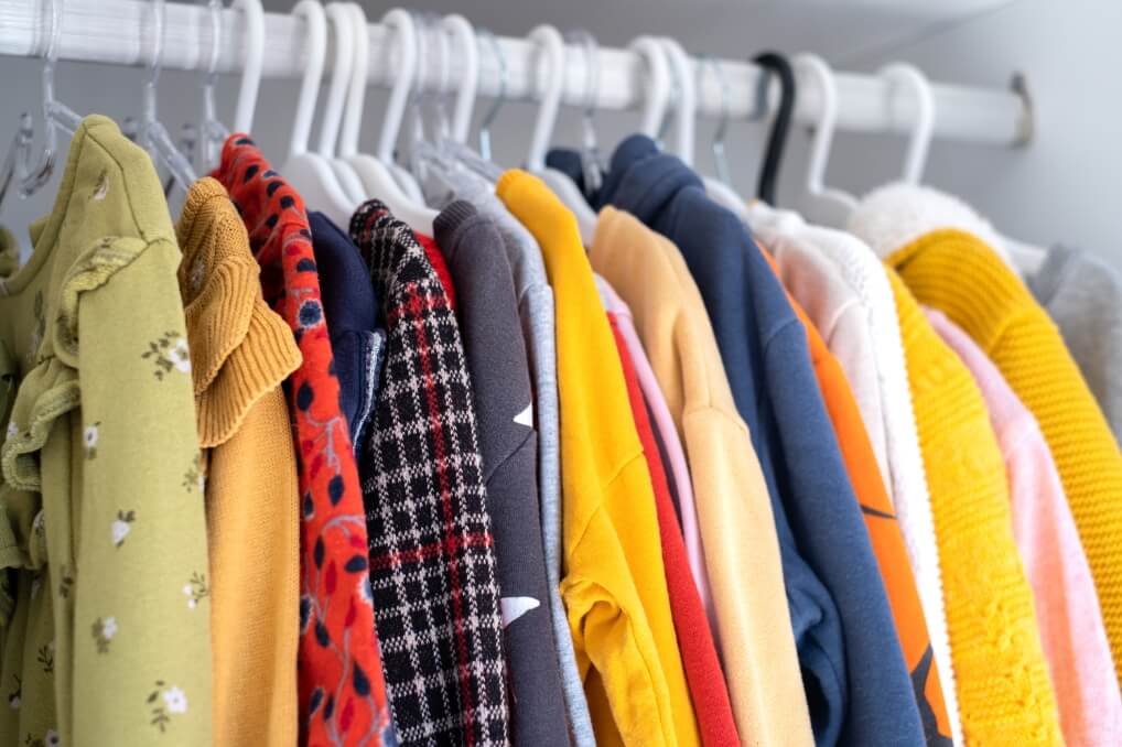 Colourful clothes hanging on hooks in a closet