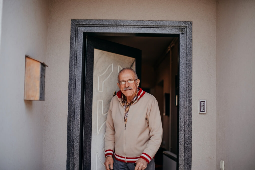 Un homme debout devant sa porte d’entrée